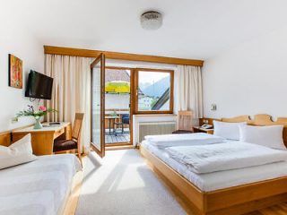 Hotel bedroom with twin beds, a balcony door opening to Innsbruck’s mountain views